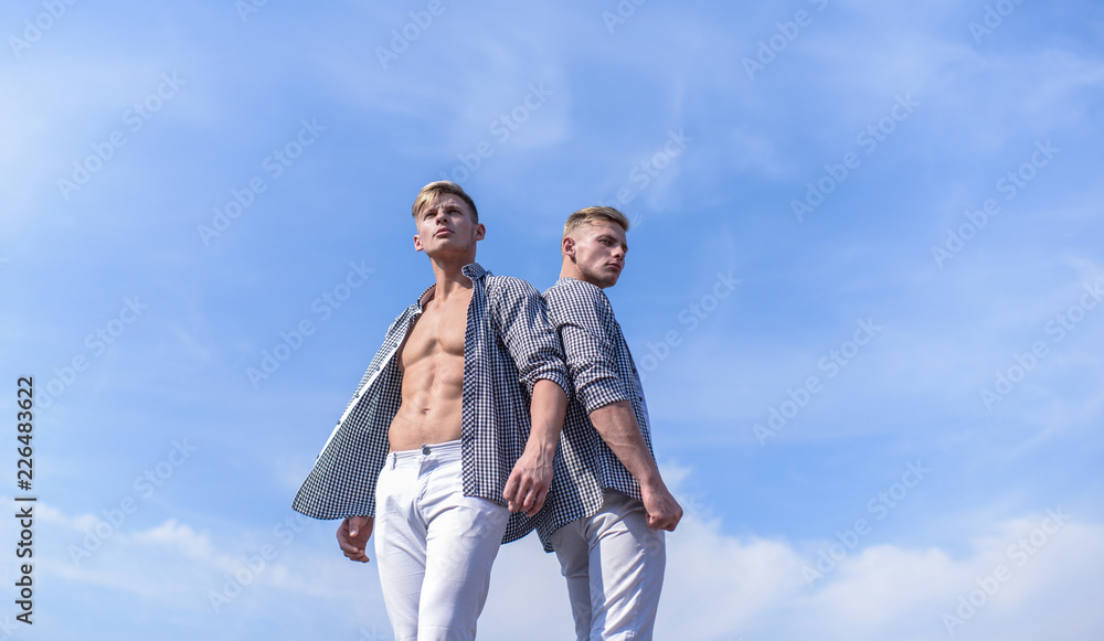 Fashionable similar outfits. Men twins brothers muscular guys posing in shirts sky background. Men strong athlete wear same shirts. Menswear and fashion concept. Brothers twins looks attractive Fashionable similar outfits. Men twins brothers muscular guys posing in shirts sky background. Men strong athlete wear same shirts. Menswear and fashion concept. Brothers twins looks attractive