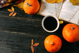 Autumn background for thanksgiving or seasonal holiday. Coffee mug, pumpkin and colorful leaves on dark background