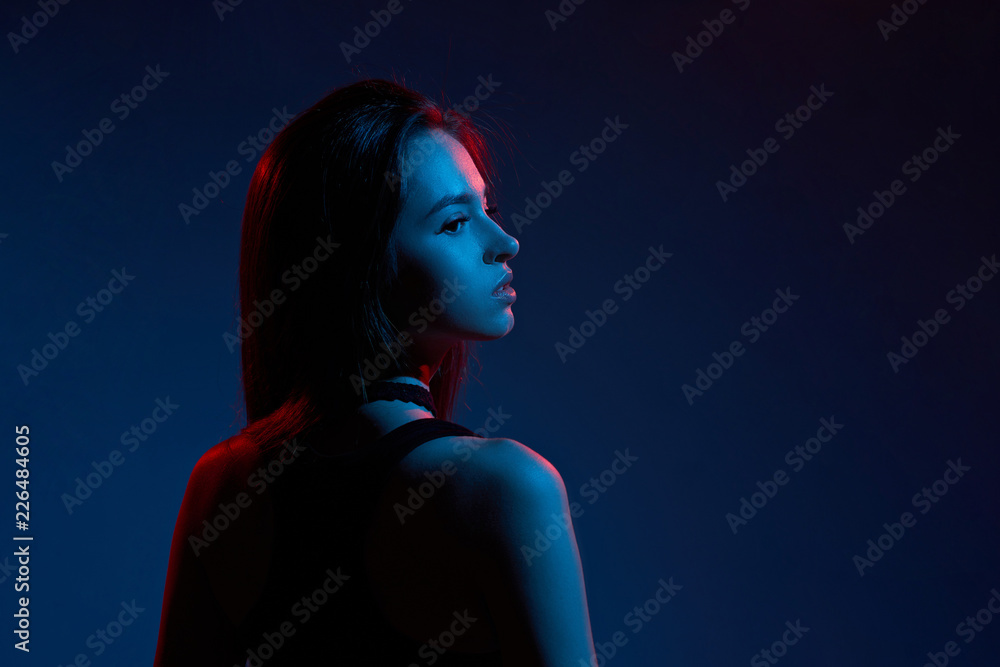 Girl high fashion model in colorful bright light poses, portrait of beautiful girl with fashionable make-up. Artistic design, colorful composition. With bright blue and red