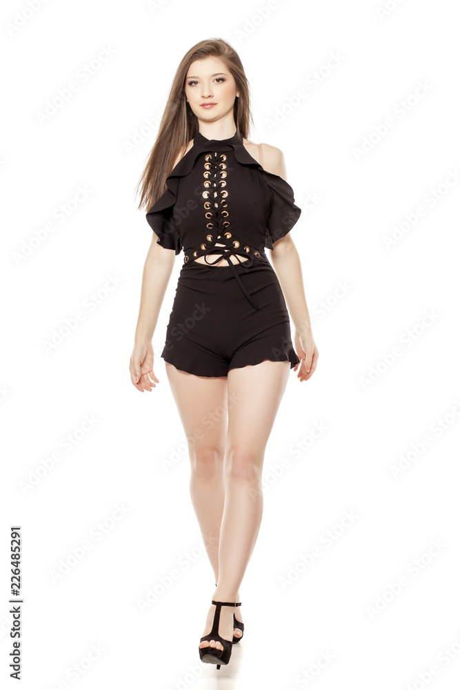 Young woman in short black trousers dress and high heels walking on white background Young woman in short black trousers dress and high heels walking on white background