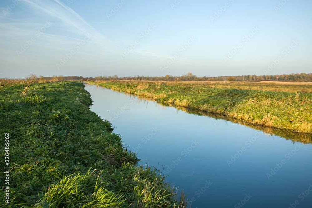Grassy shore and clean river. Poland, the Uherka River