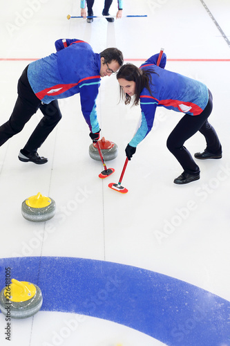 Mecz curlingowy. Młodzi ludzie na lodowisku.