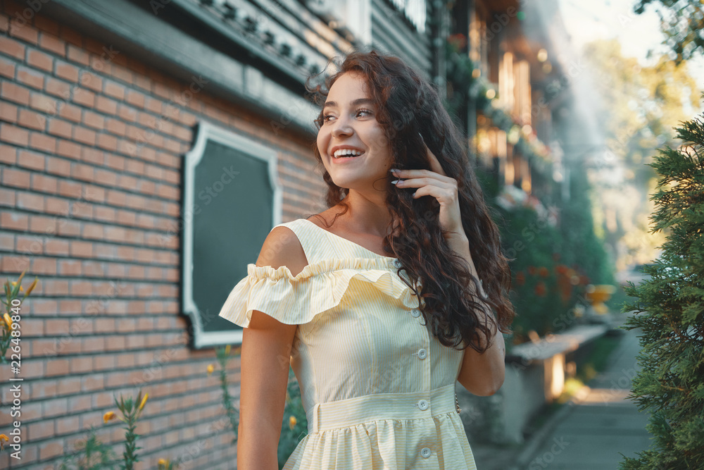 Feminine woman portrait of young smiling girl posing in the city