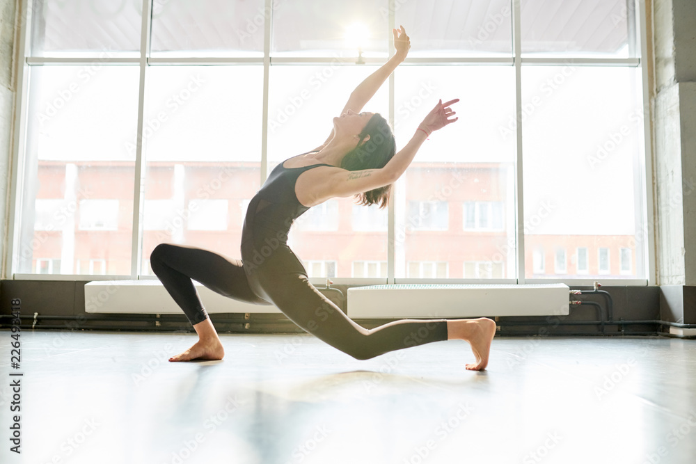 Full length portrait of contemporary young woman dancing passionately in studio lit by serene sunlight, copy space Full length portrait of contemporary young woman dancing passionately in studio lit by serene sunlight, copy space