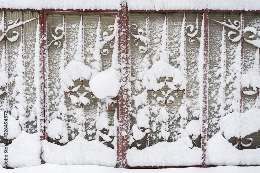 Snow-covered iron gates. winter wrought fence gates Snow-covered iron gates. winter wrought fence gates