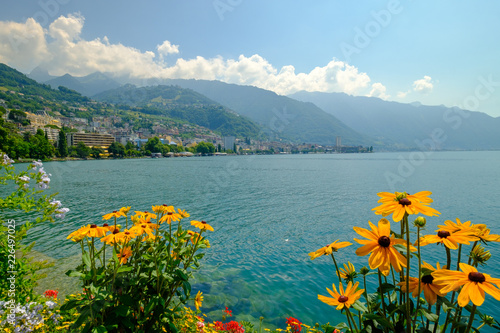 View to Montreux city from Geneva lake embankment at sunny summer day, flowers at foreground.