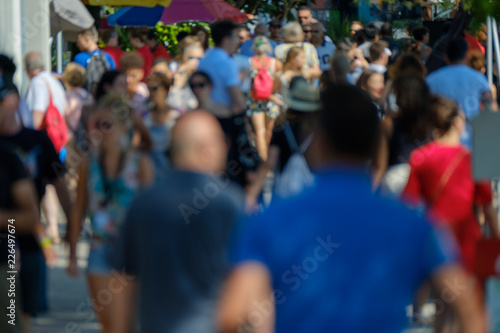 Unidentified crowd of people walking on the street at sunny day time © Anton Gvozdikov