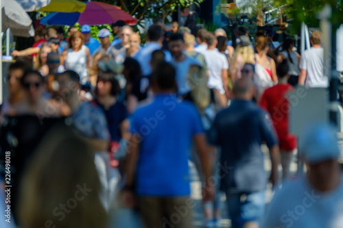 Unidentified crowd of people walking on the street at sunny day time