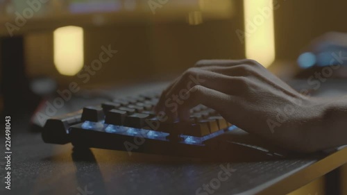 Video gamer or hacker. Hands on computer keyboard and mouse with RGB backlight. Close-up dolly panning. Shallow depth of field