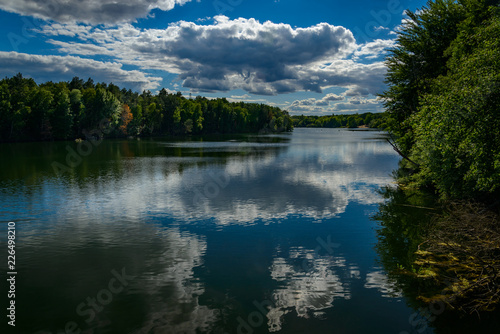 Ein dramatischer Wolkenhimmel spiegelt sich im Wasser des Flughafensees in Berlin-Tegel