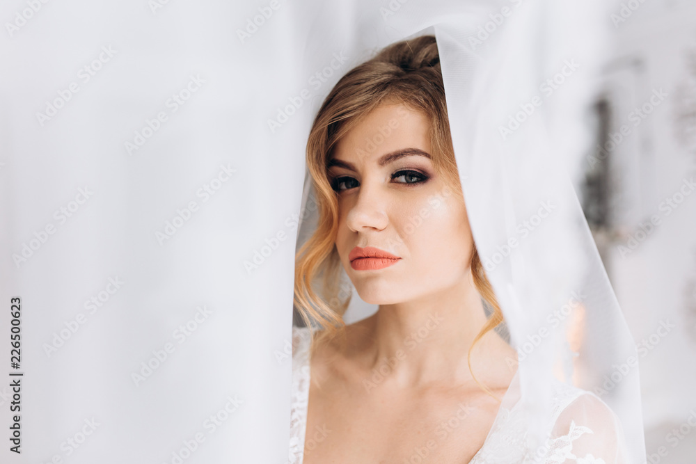 Beautiful young woman in white lingerie poses in white silk bathrobe in bright hotel room Beautiful young woman in white lingerie poses in white silk bathrobe in bright hotel room