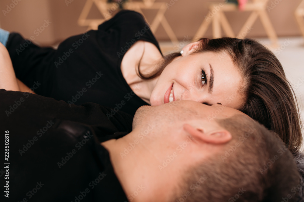 Look from above at happy young couple in black t-shirts lying on the floor Look from above at happy young couple in black t-shirts lying on the floor