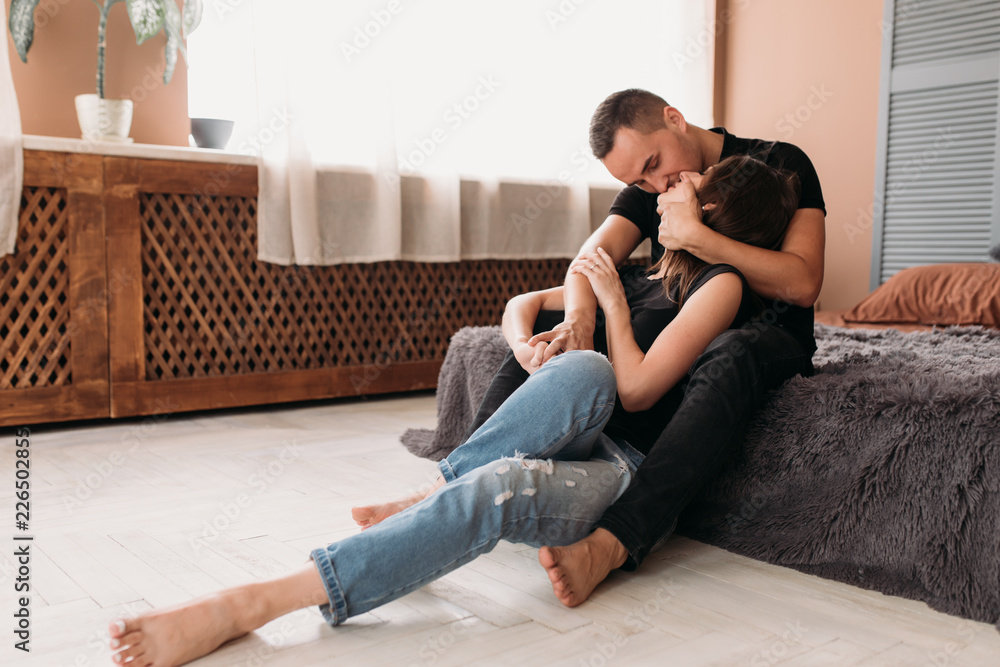 Fototapeta premium Lovely young couple dressed in casual style sits on the floor in cosy modern room