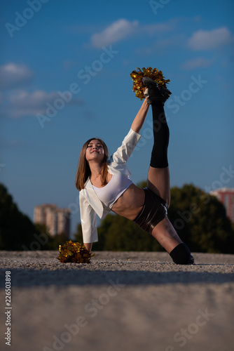 cheerleader girl with pompoms dancing outdoors on sky background