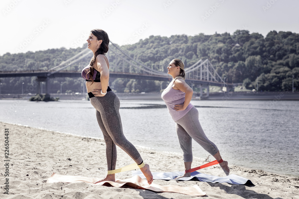 Synchronous movements. Nice young women standing on yoga mats while ...