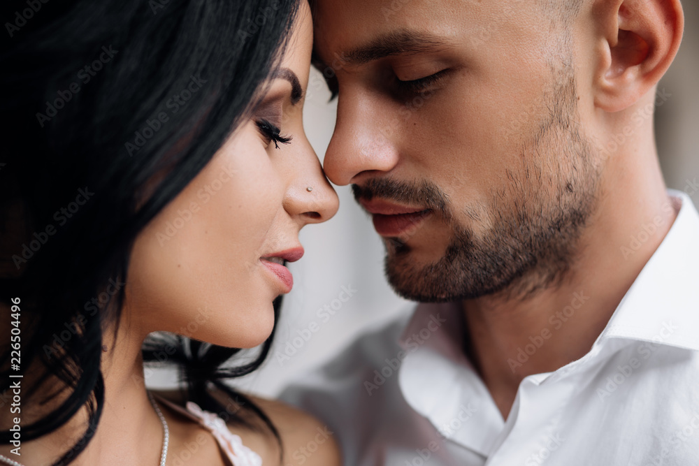 Handsome young bald headed man hugs with passion young brunette in pink evening dress Handsome young bald headed man hugs with passion young brunette in pink evening dress