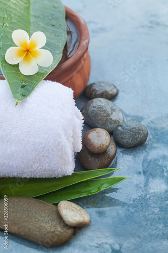Photography tropical flower and towel and stones with sunlight for massage treatment on blue background