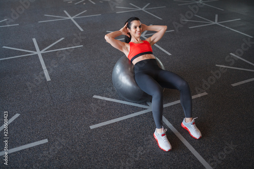 Cheerful woman doing crunches on ball