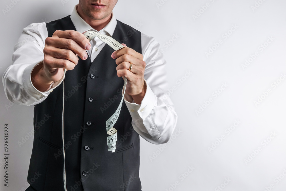 Φωτογραφία Well dressed tailor in white shirt and black suit vest holding a measuring tape