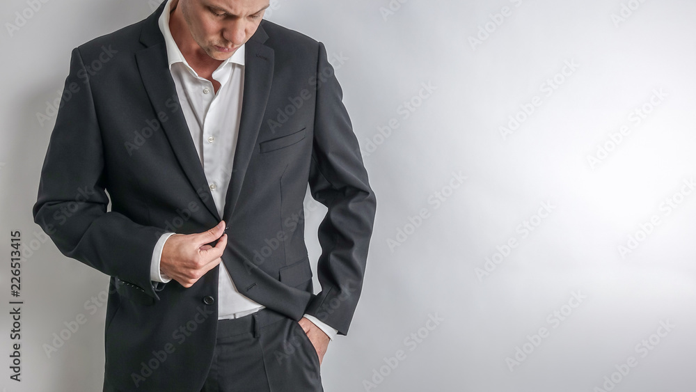 Well dressed businessman in white shirt and black suit adjusting his jacket. White background with copy space for text. Well dressed businessman in white shirt and black suit adjusting his jacket. White background with copy space for text.