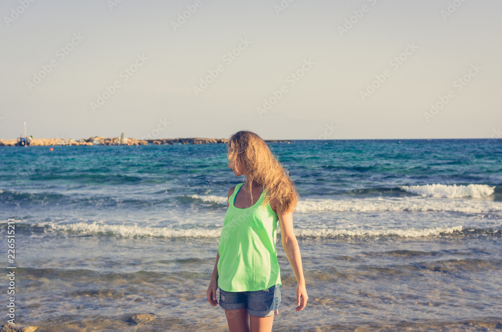 A woman with her hair loose in the wind on the background of the sea