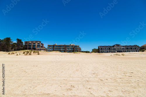 Panoramic view of a beautiful beach with apartments buildings at the background. The sky is clear and intense blue.