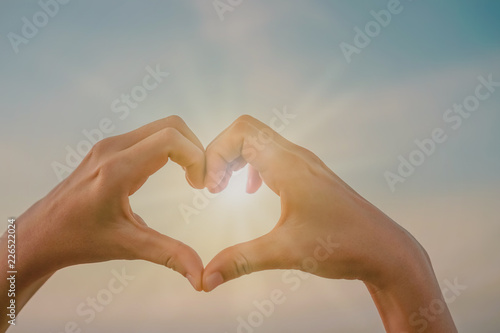 Woman hand do heart shape on nature blue sky background. © ant