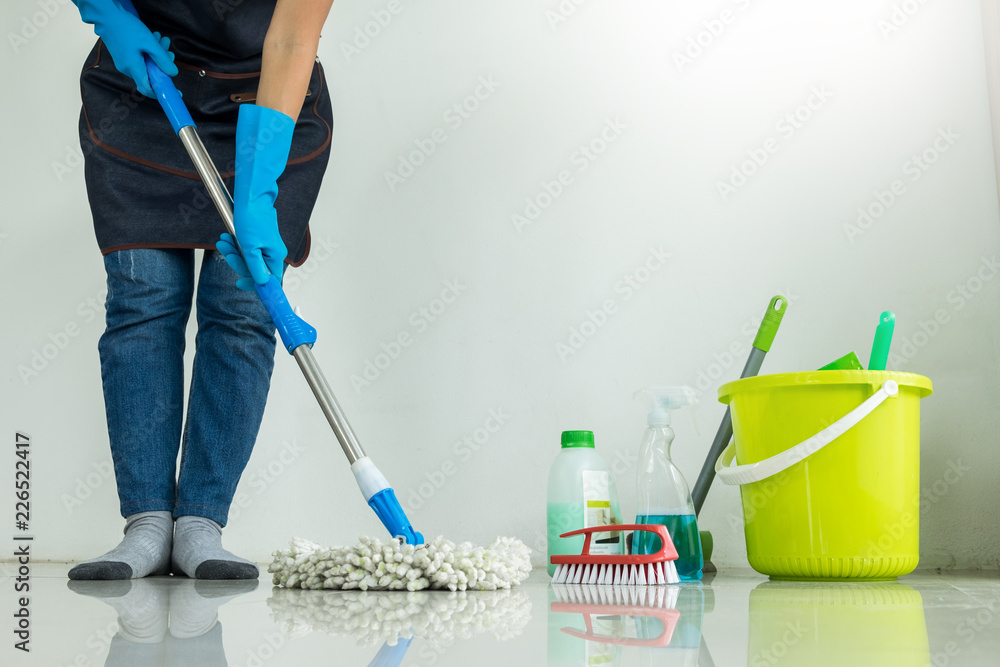 Young housekeeper cleaning floor mobbing holding mop and plastic bucket