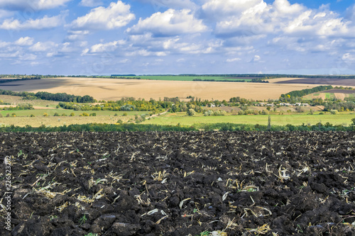 a plowed field after harvesting corn with a tractor complete with an eight-body plow against the sky and the landscape of fields
