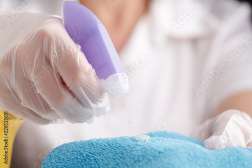 Hand in a protective glove with a washing sponge and spray sprinkle