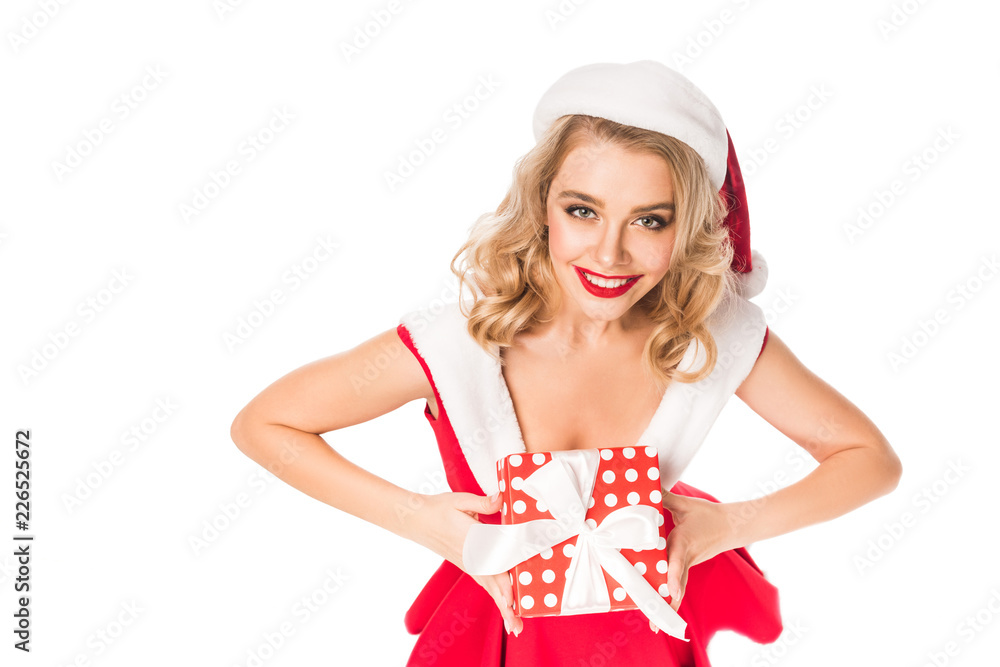 high angle view of beautiful santa girl in christmas hat holding gift box and looking at camera isolated on white