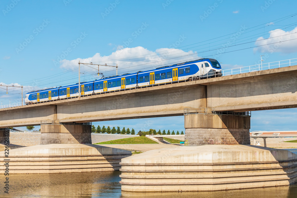 Fototapeta premium Holenderski pociąg przecinający brzegi rzeki Waal przed Nijmegen