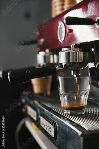 close-up view of professional coffee maker and glass cup with espresso