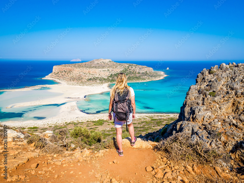 Φωτογραφία Crete, Greece: Blonde beautyful girl walking along the Balos beach with backpack and enjoying beautiful views