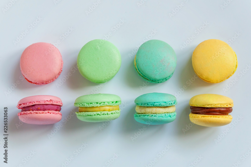 Obraz premium Sweet almond colorful pink, biue, yellow, green macaron or macaroon dessert cake isolated on white background. French sweet cookie. Minimal food bakery concept. Flat lay, top view, copy space