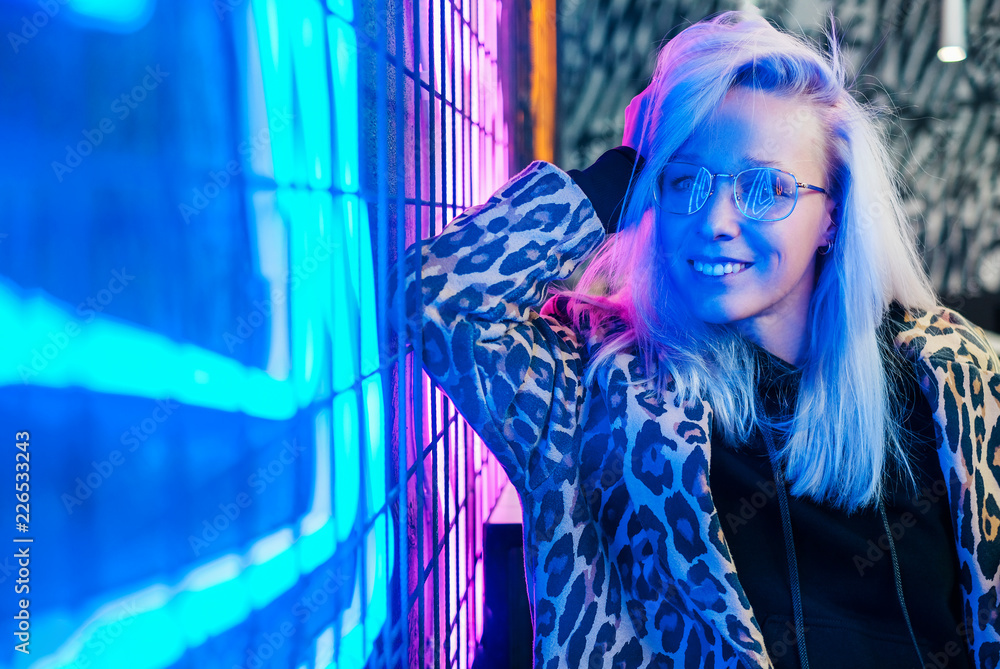 Beautiful fashionable girl sitting in bar near the neon wall Beautiful fashionable girl sitting in bar near the neon wall
