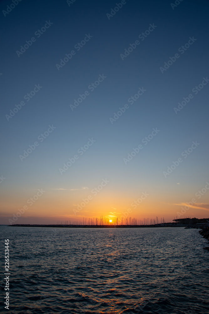 Sunset in Cecina Italy over the sea behind stone breakwater
