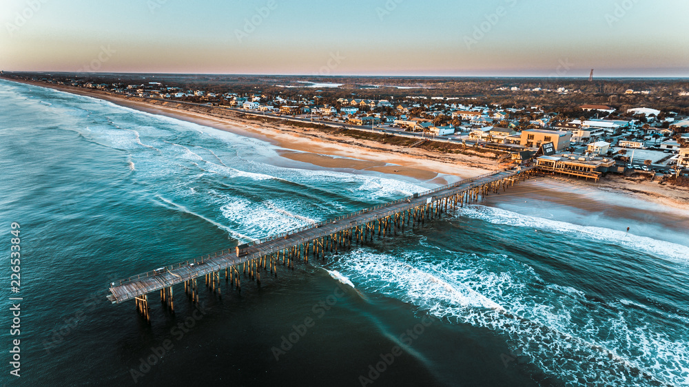Ocean beach and fishing pier aerial drone shot