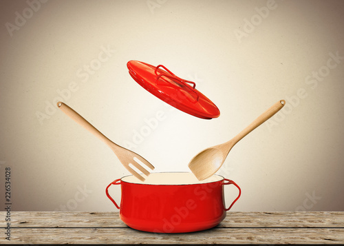 Big red pot for soup with fork and spoon
