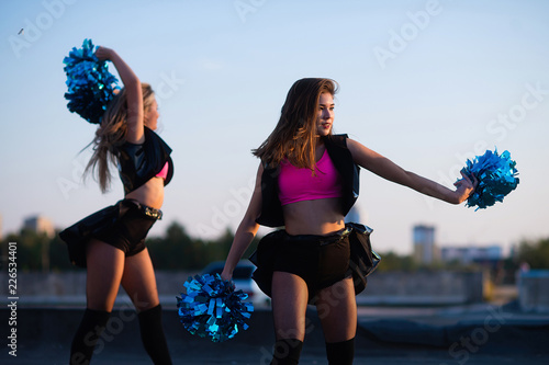 Cheerleaders dancing on the roof at sunset against the city landscape