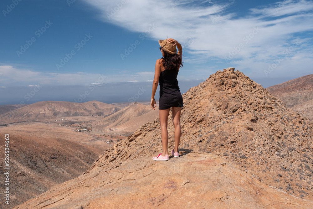 relaxed girl looking at a landscape from the top of a mountain