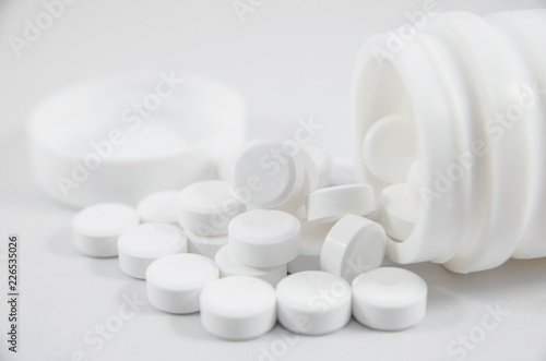 white pill on white blackground with bottle