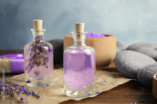 Fototapeta Naklejka Na Ścianę i Meble -  Bottles with natural herbal oil and lavender flowers on table against blurred background