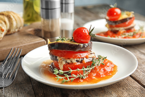Baked eggplant with tomatoes, cheese and thyme on wooden table
