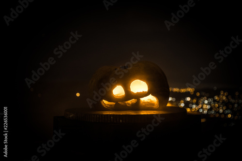 Halloween pumpkin smile and scrary eyes for party night. Close up view of scary Halloween pumpkin with eyes glowing inside at black background. photo