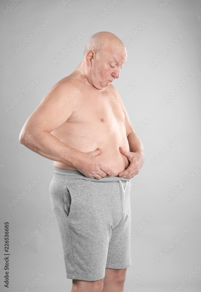 Fat senior man on grey background. Weight loss