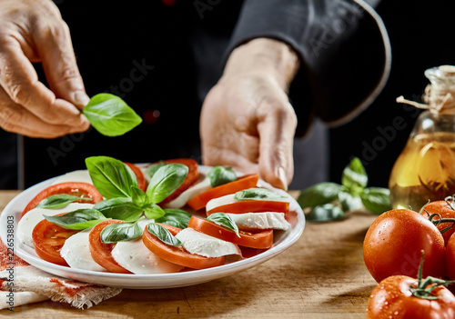 Hands of a chef preparing a Caprese salad photo
