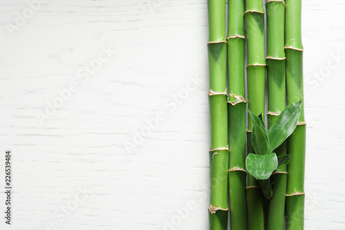 Green bamboo stems and space for text on wooden background  top view