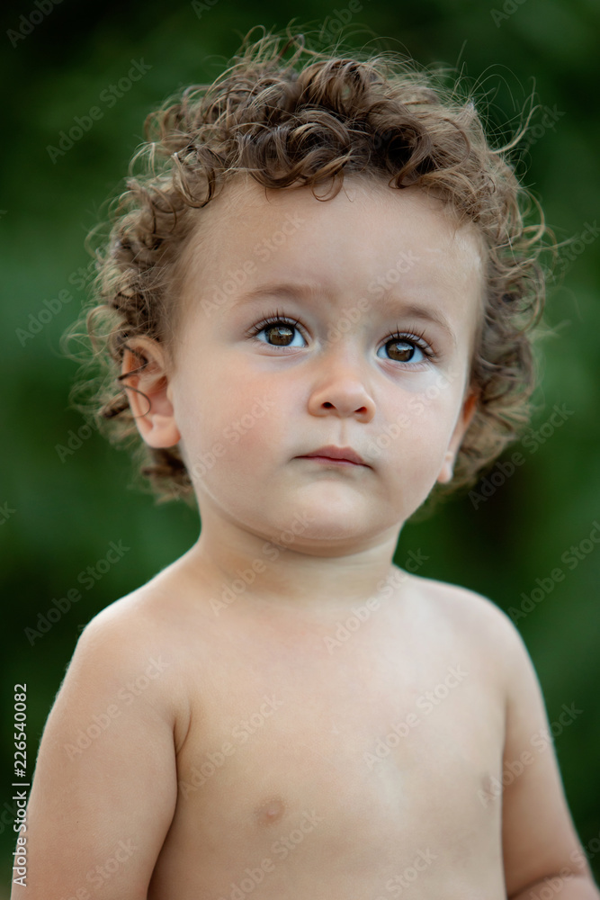 Beautiful baby with curly hair in the garden Beautiful baby with curly hair in the garden