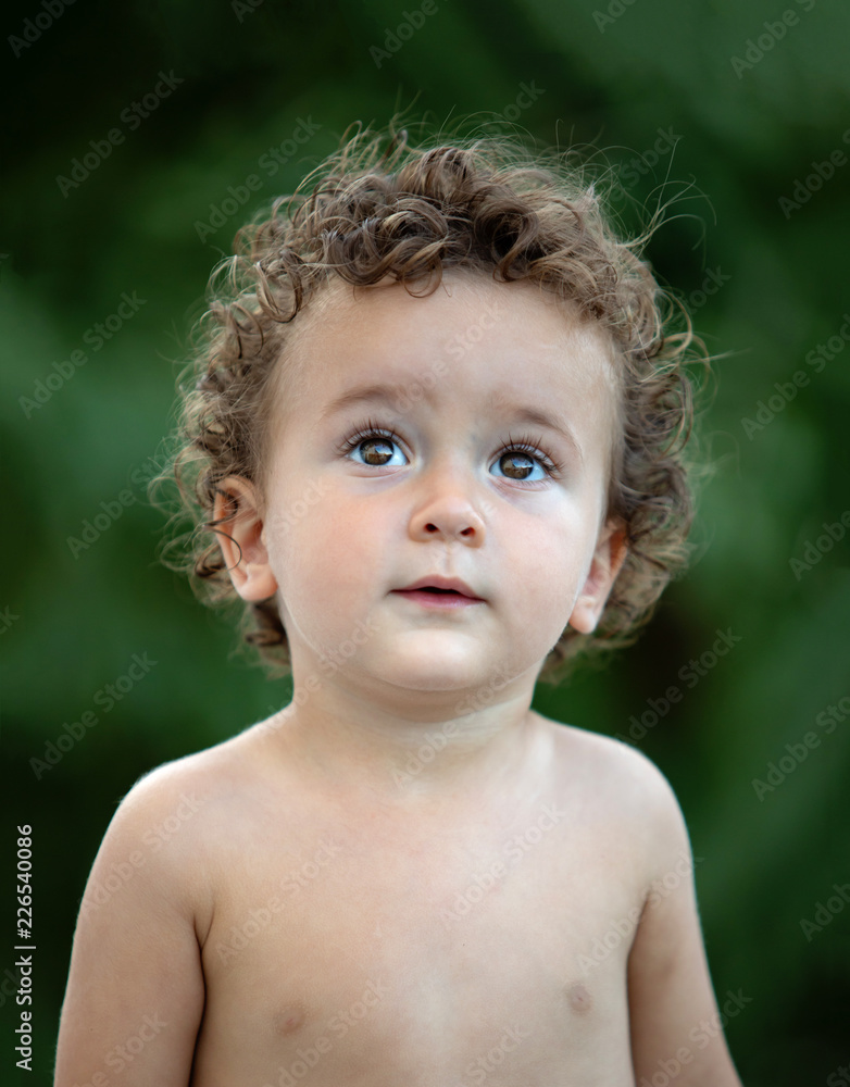 Beautiful baby with curly hair in the garden Beautiful baby with curly hair in the garden